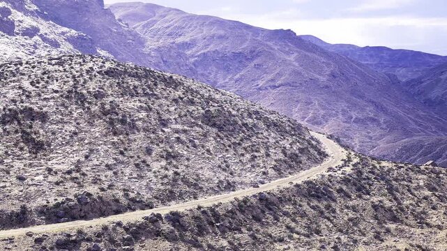 Remote expedition trail across Namibian hills, gravel track winding along ridge with panoramic views, scene ideal for overland travel planning, adventure