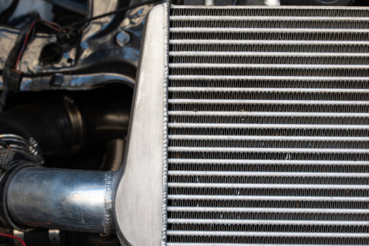 Close up of aluminum welds and cooling fins on a custom car intercooler mounted on a vehicle.