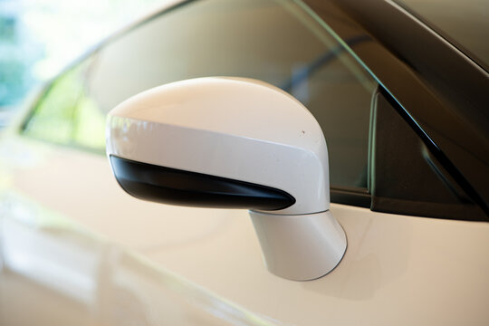 Close up of white side door mirror on a modern car exterior body panel.