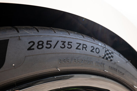 Close up view of standard tire specification text reading 285 35 ZR 20 alongside a checkered flag design embossed on a performance tire sidewall.