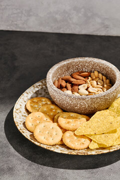 Savory cracker, corn chip and nut assortment with golden crunch on a dark setting and copy space for snack menu design
