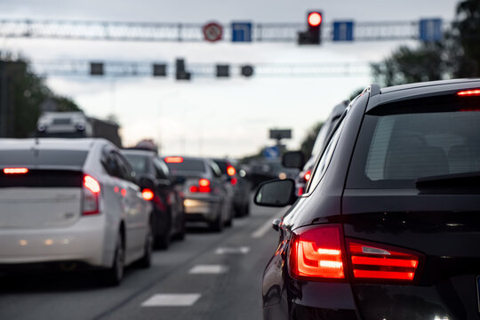 Multiple lanes of passenger vehicles waiting beneath a red traffic signal with brake lights illuminated, illustrating road congestion and signal controlled traffic flow