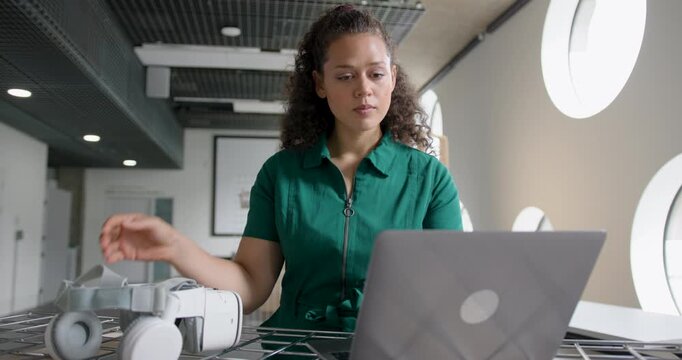 Female Engineer Working on Laptop and VR headset in Modern Office