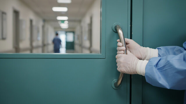 healthcare worker in gloves opening hospital corridor door