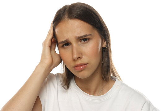 Portrait of a young woman with headache, hand on head, frustrated expression, on white background