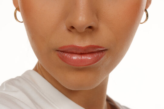 Beauty close-up of woman's lips, nose and chin front view, glossy lipstick and skin texture, on white background