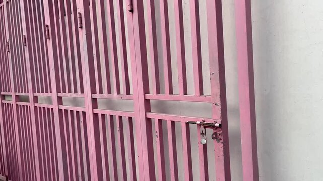 Pink Iron Gate with Locked Padlock and Shadow on Wall