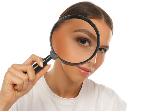Portrait of woman holding magnifying glass over eye, detective search concept, on white background