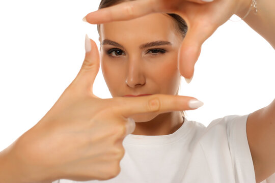 Portrait of woman making photo frame gesture with fingers, creative focus concept, on white background