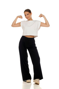 Full length fashion portrait of confident woman flexing arm muscles, strong pose, on white background.