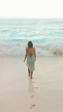 Woman in Blue Dress Walking Toward Ocean