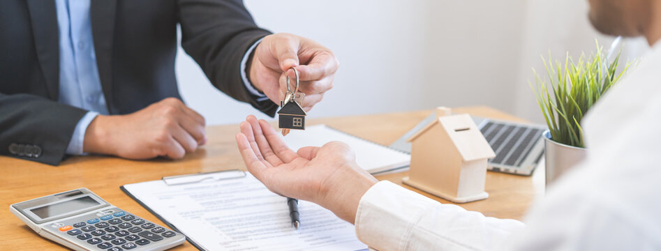 Close up agent giving a key to new owner or tenant, client after signed signature contract rental purchase, buyer apartment, home with landlord, realtor. Banker agreement mortgage loan. Property lease