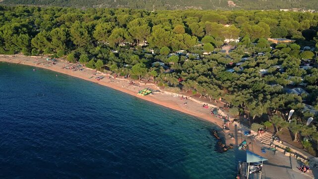 Orbiting counterclockwise aerial shot of Kovacine camp beach, town Cres, island Cres, Croatia