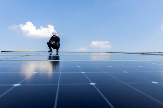 Engineer service check installation solar cell on the roof of factory. Engineers walking on roof inspect and check solar cell panel. Engineer working inspection installation solar cell on the roof