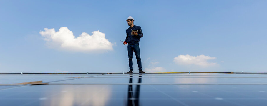 Engineer service check installation solar cell on the roof of factory. Engineers walking on roof inspect and check solar cell panel. Engineer working inspection installation solar cell on the roof