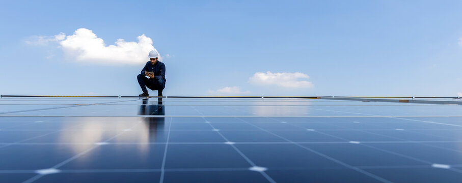 Engineer service check installation solar cell on the roof of factory. Engineers walking on roof inspect and check solar cell panel. Engineer working inspection installation solar cell on the roof