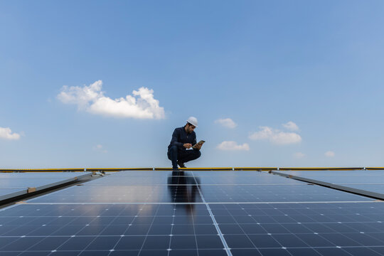 Engineer service check installation solar cell on the roof of factory. Engineers walking on roof inspect and check solar cell panel. Engineer working inspection installation solar cell on the roof