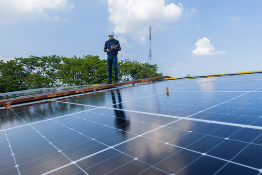Engineer service check installation solar cell on the roof of factory. Engineers walking on roof inspect and check solar cell panel. Engineer working inspection installation solar cell on the roof