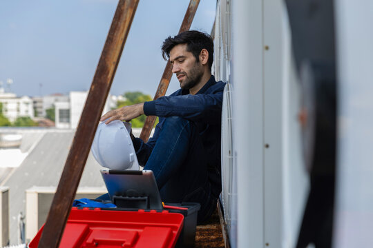 Air conditioner repairman, technician checking air conditioner, measuring device for refilling air conditioner. HVAC service technician using gauges to check refrigerant and add refrigerant.