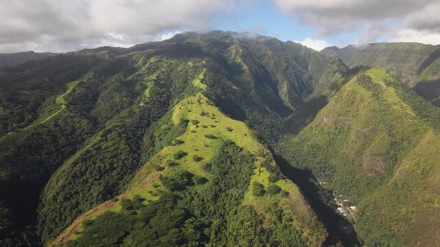 Aerial shifting left over lush green mountain ridges, deep jungle valleys, and the volcanic peak of Puu Kukui along the Waihee Ridge Trail in Maui