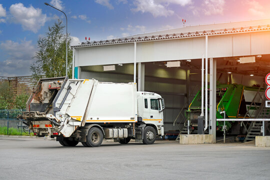 Specialized waste management vehicles parked at a professional recycling facility during the day while staff organize city collection services