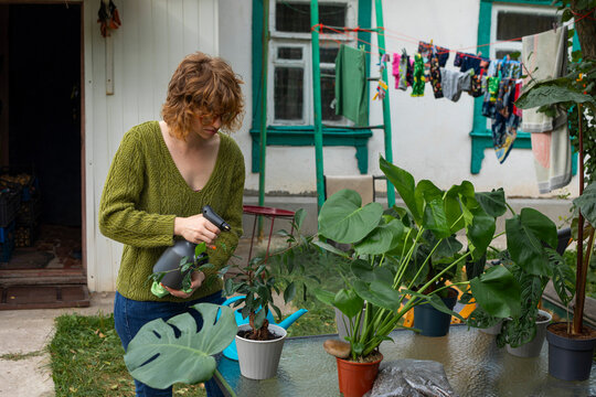 Woman spraying potted houseplants in a backyard garden