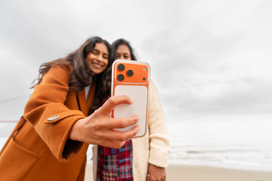 two women take fun selfie outside with iphone