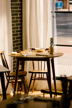 Small wooden table set for two in sunlit minimalist restaurant
