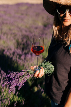 Woman holds wine glass in lavender field.