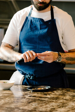 Chef peeling almonds with a specialized tool in a gourmet kitchen