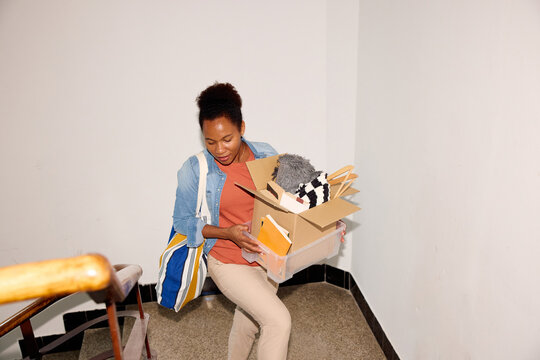 Woman ascends the stairs with a box of items.