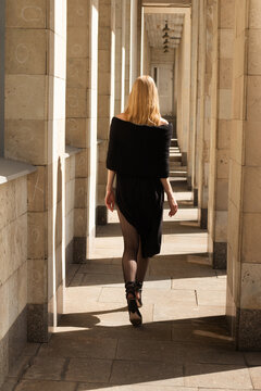 Street style with young blonde woman   walking away from the camera.
