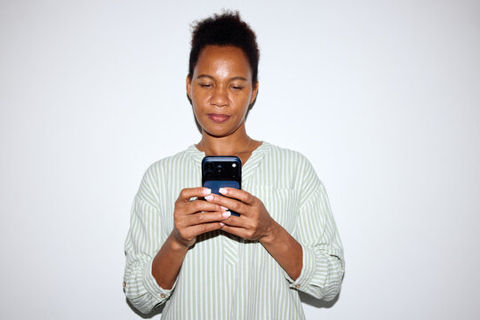 Woman checks her phone against neutral background