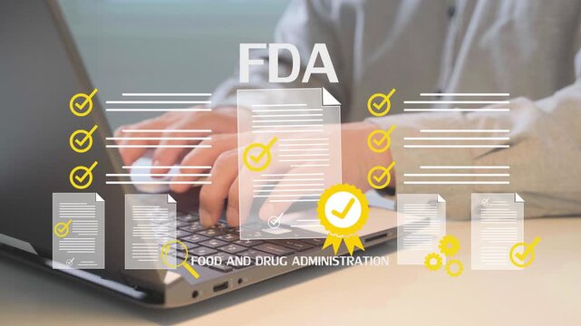 Person typing on laptop with FDA documents floating around. Documents show approval marks and compliance symbols. Image reflects regulatory work in healthcare or pharmaceutical field