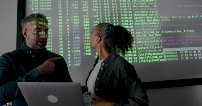 Co-Workers Reviewing Data Presentation Together, using Laptop and Projection Screen in Office