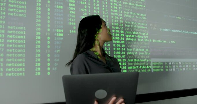 Confident Female Professional Analyzing Data on Projection screen, using Laptop