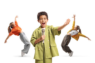 Boy singing into a microphone with two girls dancing behind him