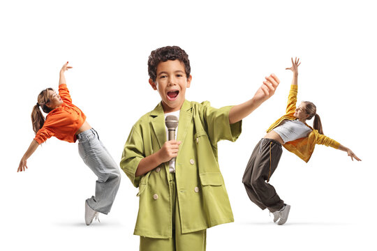 Boy singing into a microphone with two girls dancing behind him