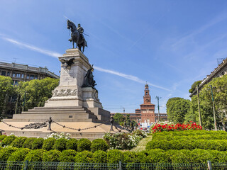 Giuseppe Garibaldi's equestrian statue stands in Milan's Piazza Cairoli, with Castello Sforzesco rising beyond the gardens under a bright blue sky.  © Dan Van Pelt
