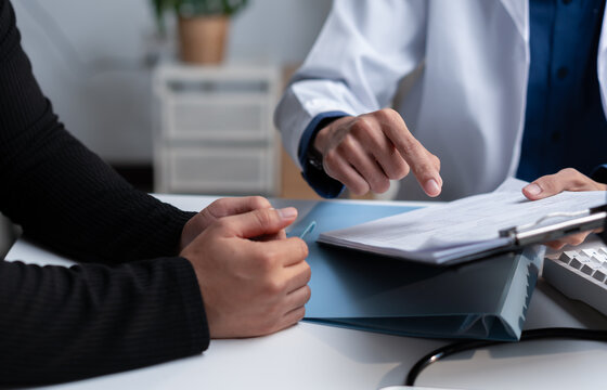 Doctor reviewing medical records with a patient during consultation, explaining healthcare documents, diagnosis, treatment options, clinical results, insurance and personalized care planning.