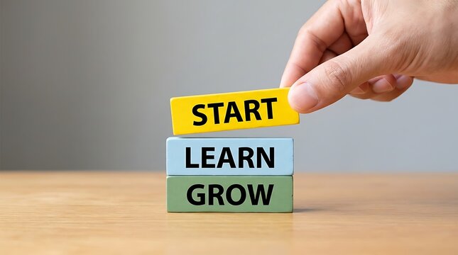 A hand places a yellow block with the word start on top of blue learn and green grow blocks, symbolizing progress and personal development stages for success.