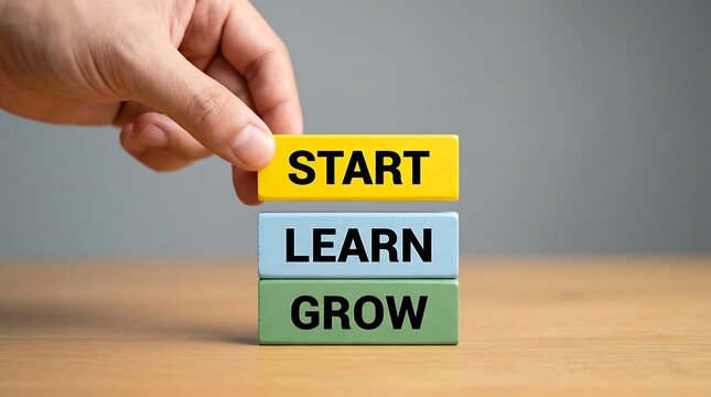 Hand stacking wooden blocks with words start learn grow symbolizing personal development and business progression.