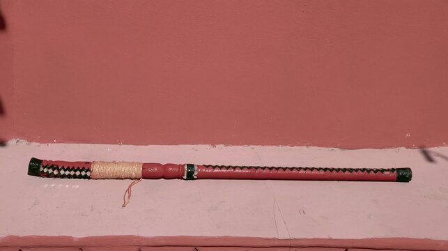 Navratri dandiya sticks with crimson lacquered finish and mirror trim, resting on a matching surface with copy space for holiday greetings