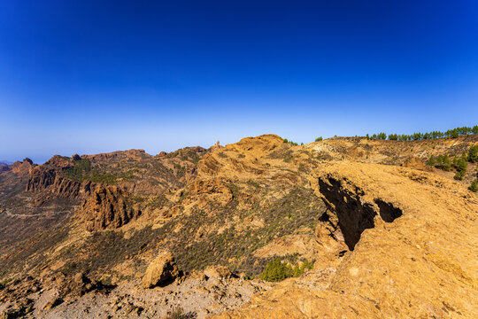 Volcanic mountain landscape on Gran Canaria, Canary Islands, with rugged golden rock formations beneath a clear deep blue sky.