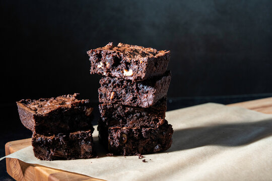 Triple chocolate brownies in a stack on a dark surface 