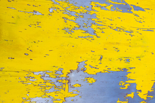 High resolution grunge texture of bright yellow paint peeling and flaking off a weathered blue industrial surface