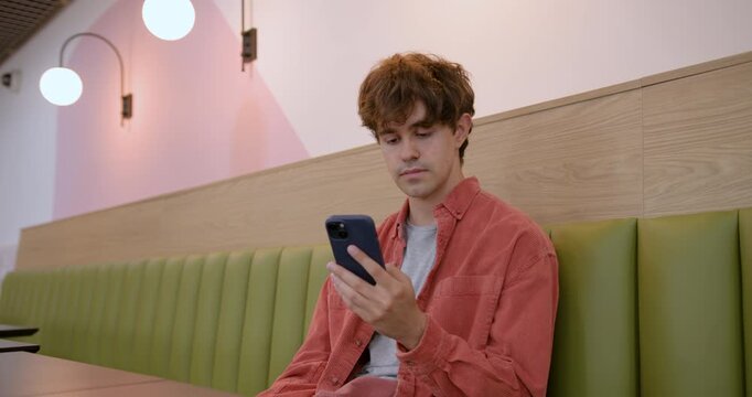 Young Adult Man Using Smartphone in Cafe