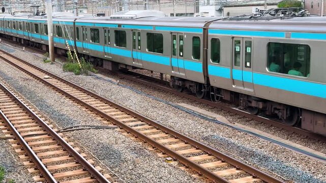 Keihin-Tohoku Line commuter train gliding past parallel tracks in the urban rail corridor near Tsurumi, Yokohama