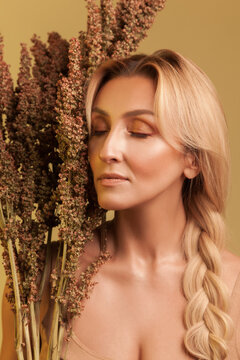 Elegant lady with braid standing with eyes shut near large dried plant arrangement and feeling harmony during mindfulness session isolated over yellow background