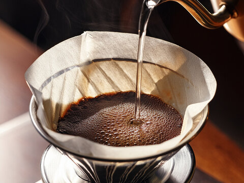  freshly ground coffee being poured into a coffee filter